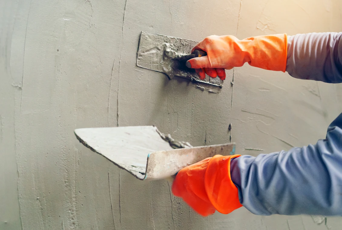 Worker applying plaster with trowels